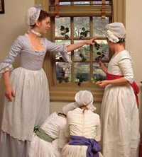 Grace McArthur, Caroline Hollis, Suzanna Winder, and Amy Player, left to right, decorate windowpanes in the Geddy House with sprigs of holly for Christmas.