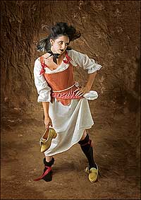 Theatrical interpreter Meg Brown holds a golden-yellow silk-covered hand-built shoe by Sara Juniper while contemplating what to put on over her lace-trimmed linen shift, small pink hoops, and rose-pink damask stays.